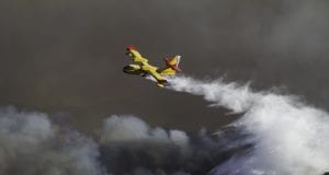 Wild fire close to houses being fought with airplanes and helico