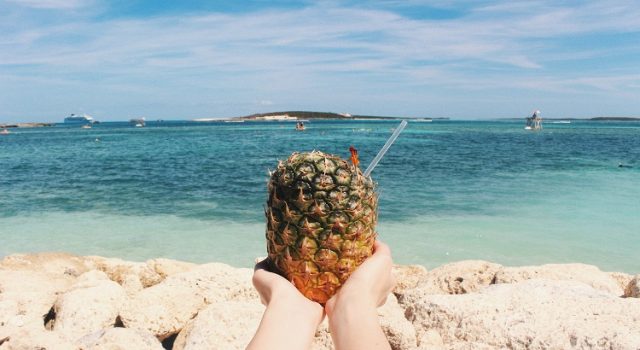 hands hold pineapple on a beach