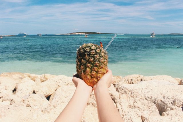 hands hold pineapple on a beach