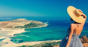 Νεαρή κοκκινομάλλα κοπέλα με καπέλο και φόρεμα με θαλάσσια ακτή στον Μπάλο, Κρήτη, Ελλάδα