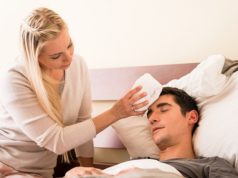 Young caring woman holding a cold compress on the forehead of he